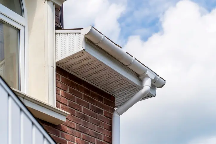 White half-round gutters installed on a brick house